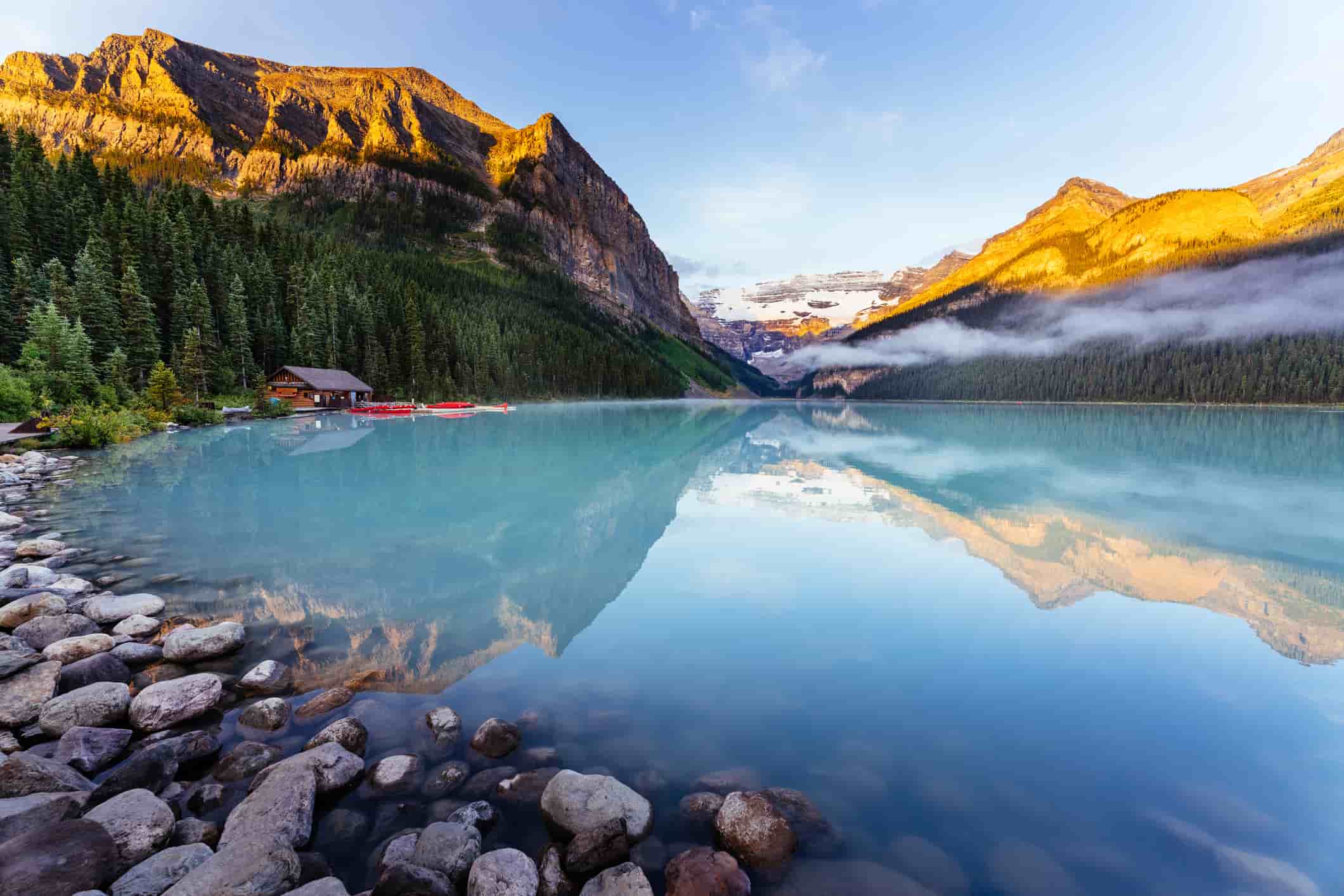 Lake Louise at sunrise, calm water and light on the mountain tops.