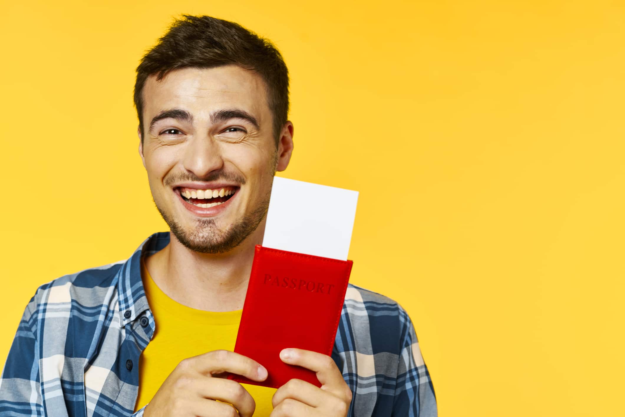 a happy young man holding a passport and tickets