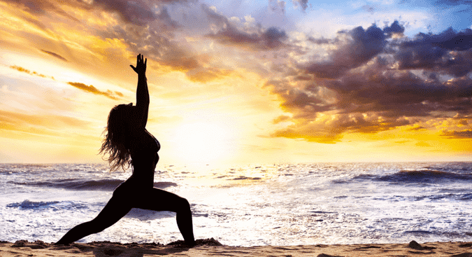 practicing yoga at the beach