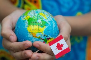 a person holding the world globe and Canadian flag
