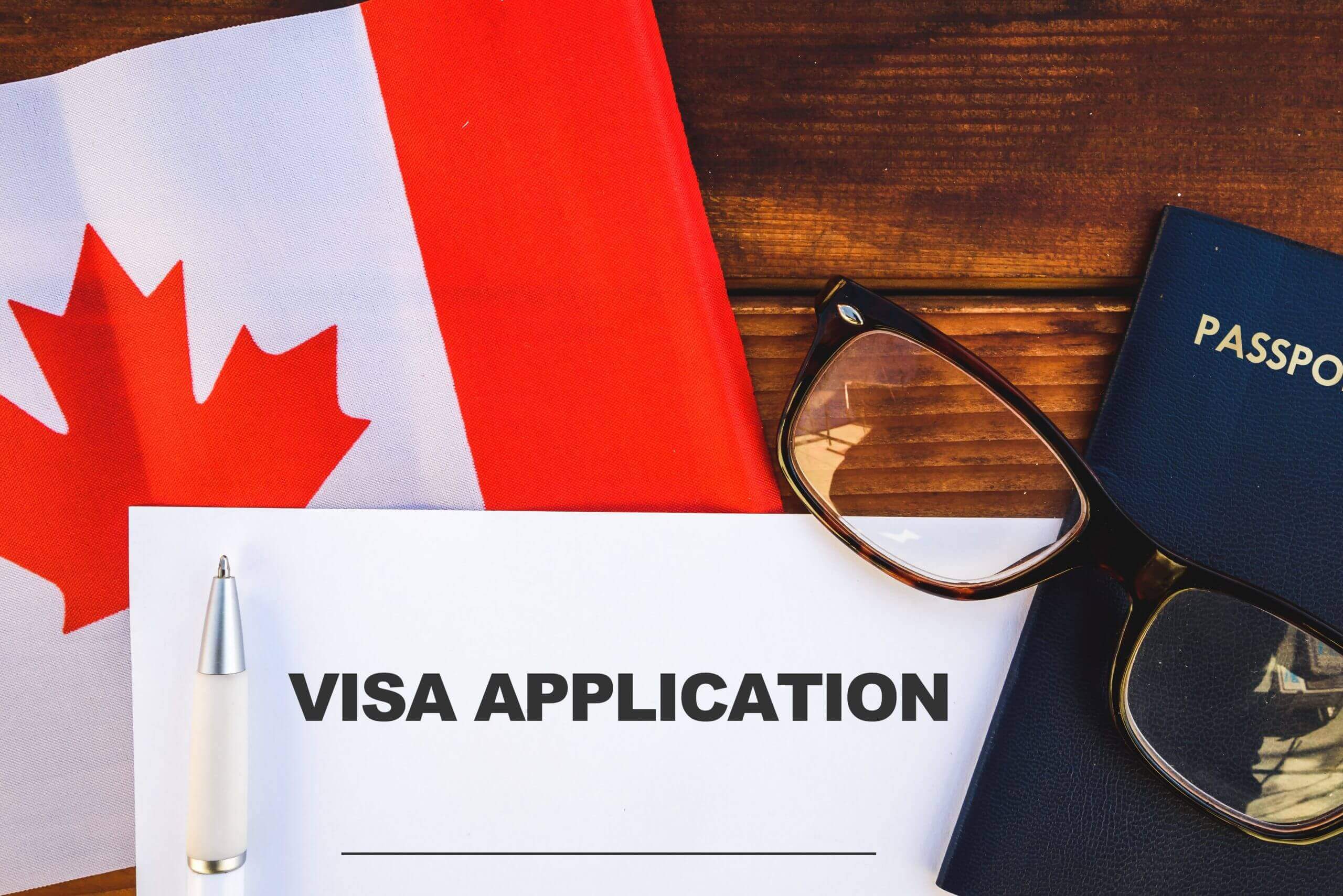 Canada visa application form with passport and eye glasses